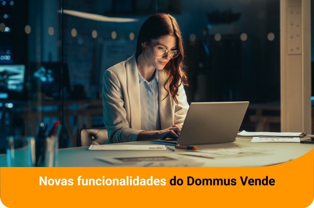 Mulher de óculos e blazer claro trabalha em um laptop à noite em um escritório, com o texto "Novas funcionalidades do Dommus Vende" em uma faixa laranja.